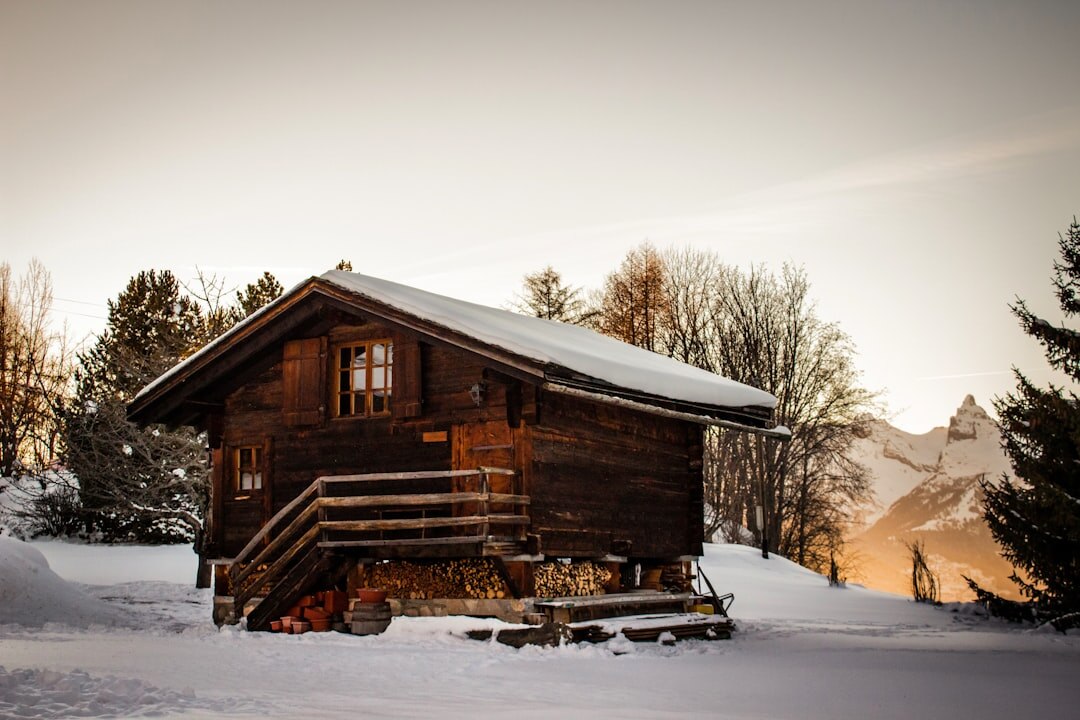 Luxury alpine chalet exterior covered in snow at dusk